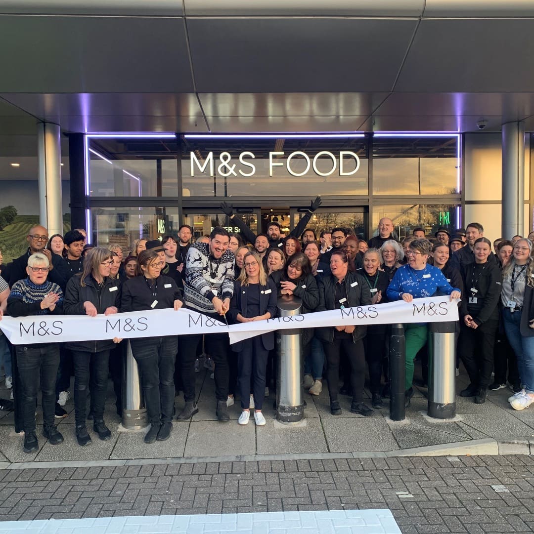 A group of people gathered outside an M&S store to cut the ribbon for opening day